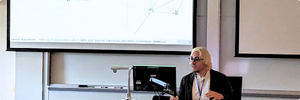 Daniel Braconnier speaks in front of a podium; a slide with text displays in the background.