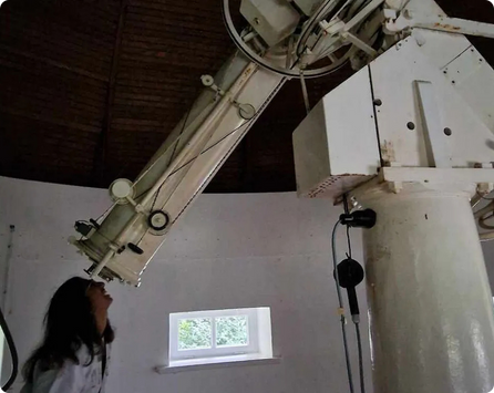 Portrait of Shreya looking through a telescope.